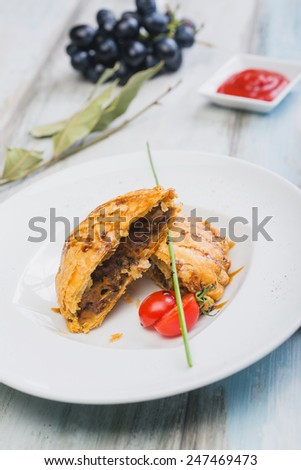 Peruvian snack called Empanada pie filled with ground beef meat and vegetables on a wooden table