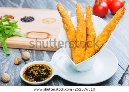 Tempura Shrimps (Deep Fried Shrimps) with sweet sauce on a wooden table with tomatoes and herbs