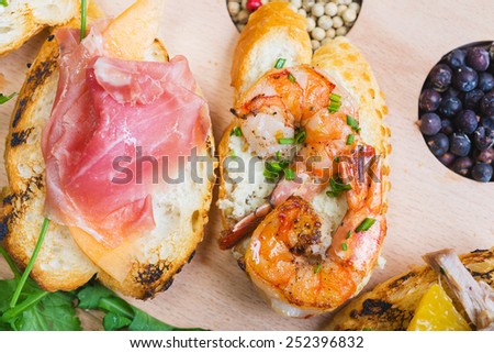 mix of traditional Spanish tapas on a wooden plate with decor, tomatoes and spices