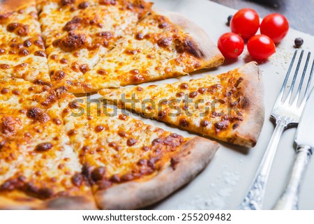hot delicious homemade pizza margarita cut into pieces on a wooden table with a creative decoration of the ingredients
