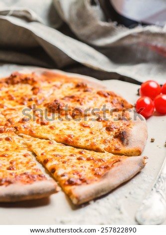 hot delicious homemade pizza margarita cut into pieces on a wooden table with a creative decoration of the ingredients
