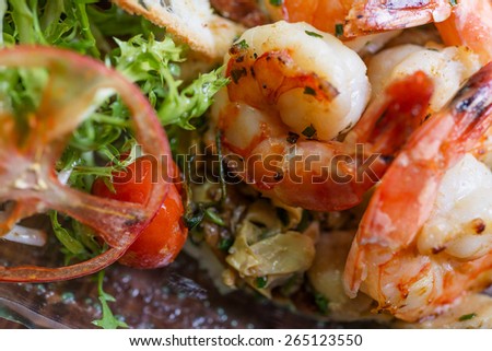Healthy and fresh salad with shrimps and vegetables serving on the plate on a wooden table in a restaurant with decor