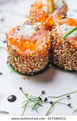 traditional japanese rolls with salmon and philadelphia cheese sesame and red caviar on a white plate with decor