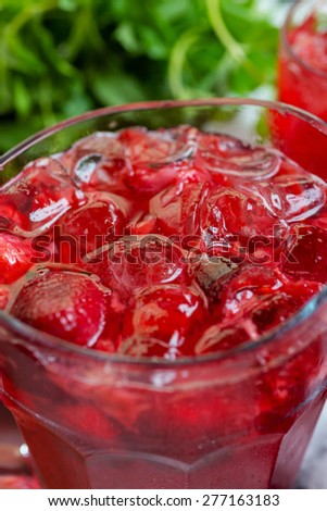 a decanter of bright summer cool refreshing strawberry lemonade on a table with a creative composition with ice, strawberries and fresh mint, soft focus