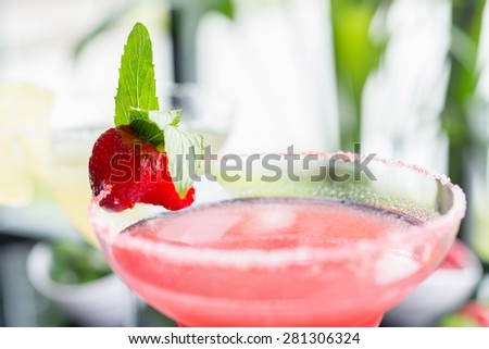 close up details of strawberry daiquiri on a table in a restaurant with creative decoration of salt on the edge of the glass with fresh mint and berries. soft focus
