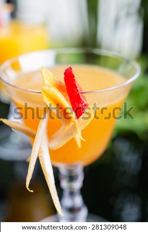 bright glasses with cold alcoholic cocktail with orange juice on a wooden table in a restaurant with creative decoration of berries, fresh mint and orange slices. soft focus