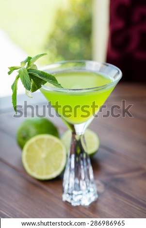 refreshing glass of cold apple lemonade with mint and ice on a wooden table in a restaurant with a creative decoration of mint leaves and fresh apples. soft focus