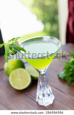 refreshing glass of cold apple lemonade with mint and ice on a wooden table in a restaurant with a creative decoration of mint leaves and fresh apples. soft focus
