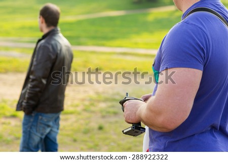 adult man in a summer park holds a radio control model in the background with a man who watches the movement. beautiful bokeh and soft focus