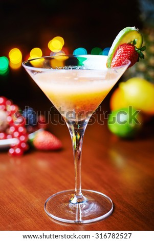 glass of bright tropical alcohol cocktail with passion fruit or lemonade with beautiful decoration on a table in a restaurant with backgrounds of bright colored lights. soft focus.