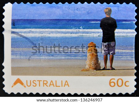 AUSTRALIA - CIRCA 2011: Stamp printed in australia dedicated to living australian, shows young man with his dog watching the sea, circa 2011