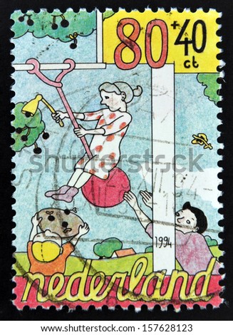 HOLLAND - CIRCA 1994: A stamp printed in The Netherlands dedicated to Child Welfare shows Helping to balance woman picking cherries, circa 1994