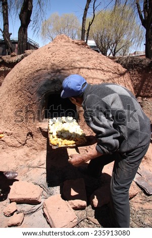 BOLIVIA, MOLLABAMBA, 21 SEPTEMBER 2013 - Indian old man cooking in Traditional Horno Clay Oven in the village of Bolivia, South America
