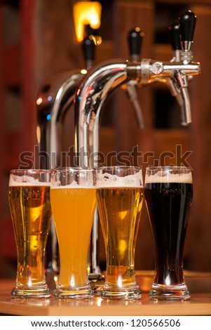 Four glasses of beer against beer tap
