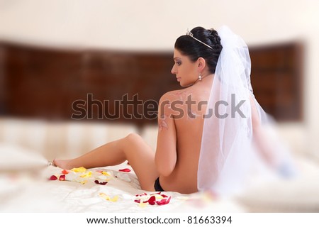 girl in veil sitting on the bed with his back to the camera