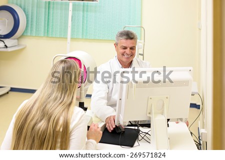 Optometry concept -  young woman having her eyes examined by an eye handsome elderly doctor. Topography of the cornea.
