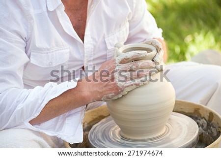 potter working on a potter\'s wheel with white clay