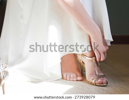 Closeup detail of bride putting on high heeled sandal wedding shoes