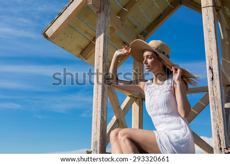 young attractive girl posing on a lifeguard tower on the beach