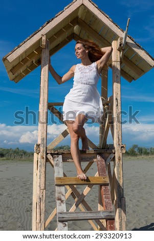 young attractive girl posing on a lifeguard tower on the beach