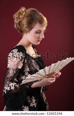 pretty young lady  in old time ball dress with fan  in  style of the end of XIX century