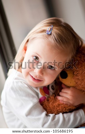 Closeup portrait of adorable toddler girl cuddling with a teddy bear