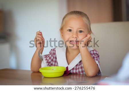Cute little girl in school uniform having breakfast in the morning before school