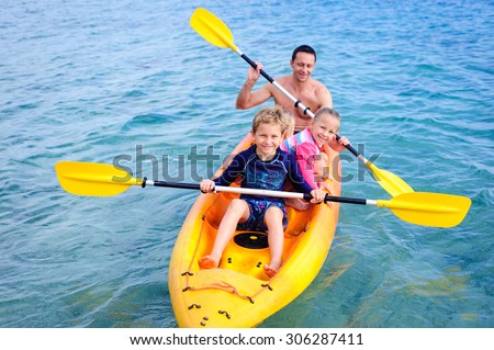 A happy family: dad and his children- a boy and two girls kayaking in the blue waters of the ocean
