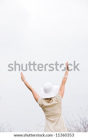 Woman standing outside with her arms up in the air with her back to the camera