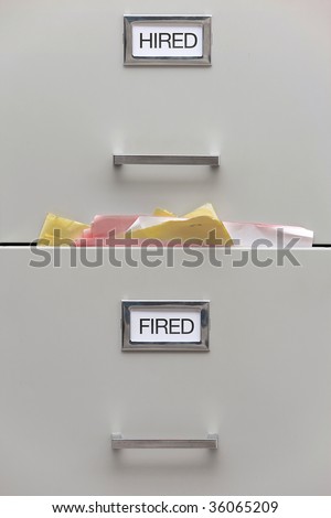 Close up shot of a filing cabinet with labels reading hired and fired.  The \'fired\' drawer is very full.  Vertically framed shot.