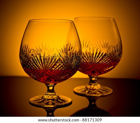 two cut glass brandy glasses in low light