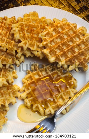 Waffles are mall crisp batter cake, baked in a waffle iron and eaten hot with butter or syrup.
