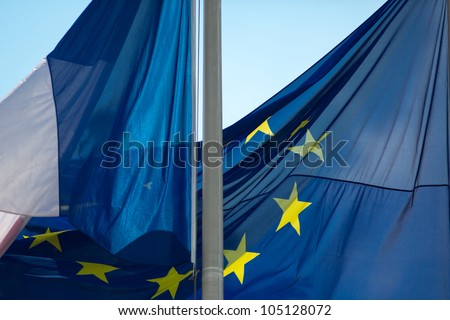 French flag and European EU flag wave in bright sun against a blue sky