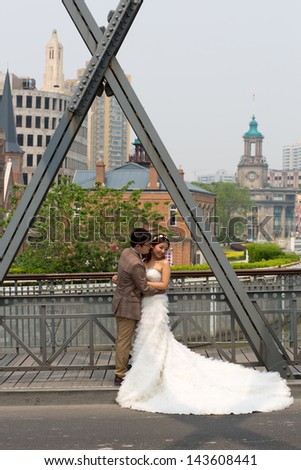 SHANGHAI- APRIL 29: Unidentified Asian couple holding each other during a pre-wedding photograph session on a bridge in the center of Shanghai, April 29, 2013, Shanghai, China