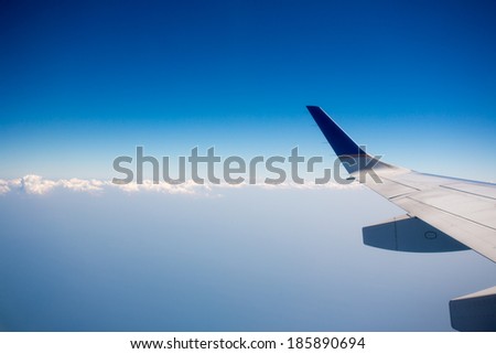 View of jet plane wing with crystal blue sky in the background and clouds with copy space.