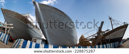Panorama of wooden fishing boats under construction in shipyard in the harbour of Essaouira against a blue clear sky, Morocco.