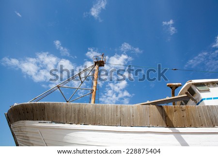 Side view of a wooden fishing boat under construction in shipyard in the harbour of Essaouira against a blue clear sky, Morocco.