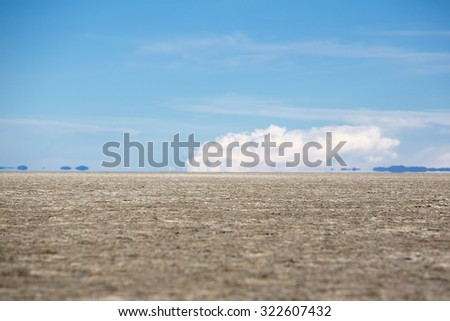 View of the Salar of Uyuni against a blue sky during the dry season with very low angle, the salt plains are a completely flat expanse of dry salt. Bolivia