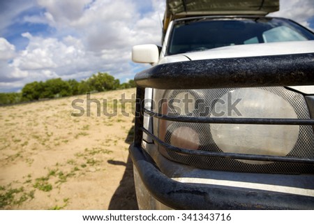 EPUPA FALLS, NAMIBIA, JANUARY 7: Front view of protection bars and headlights from off road vehicle in the Kaokoland with the bush and cloudy blue sky in the background, Namibia 2010
