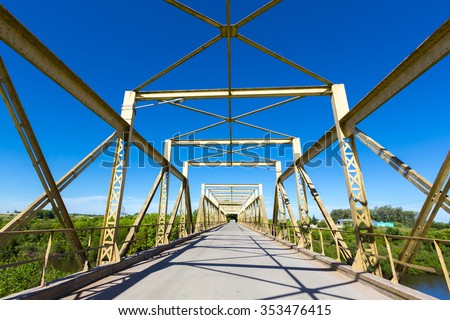 Road through old yellow metal bridge tunnel with clear blue sky in Uruguay