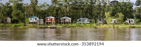 Panorama of wooden houses on stilts and Indian natives on the Amazon river bank near Manaus with the rain forest in the background. Amazonas State. Brazil 2015