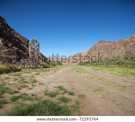 Kaokoland game reserve in Namibia, sand track going toward the Skeleton Coast Desert with a blue sky