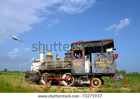 Old steam train rusting in tropical heat and humidity, Cuba under a blue sky