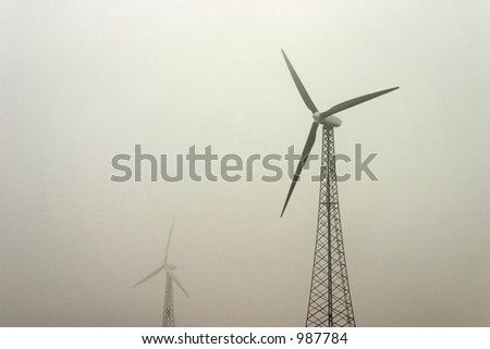 Windmill turbines on a foggy day provide power for an alternative renewable energy resource