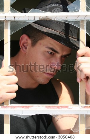 Young man behind bars en broken window
