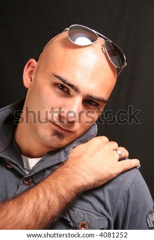 Portrait of a young man shaved head with sunglasses serious