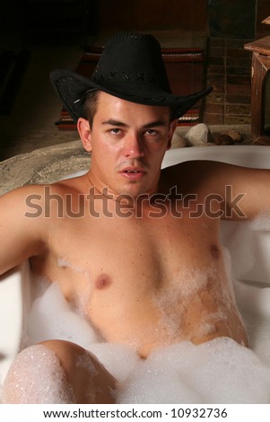 sexy muscular young man in a bubble bath spa with a hat