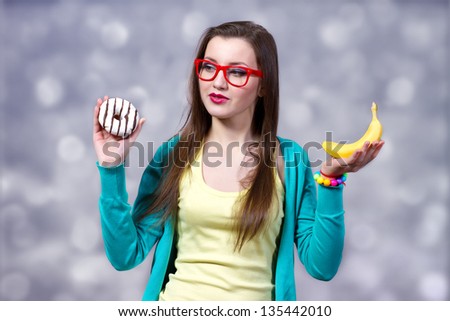 Girl trying to make choice between donut and banana