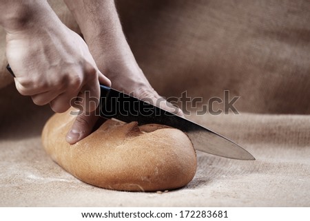 Male hands cut bread with knife