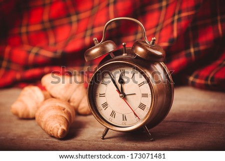 Three croissants at table and alarm clock